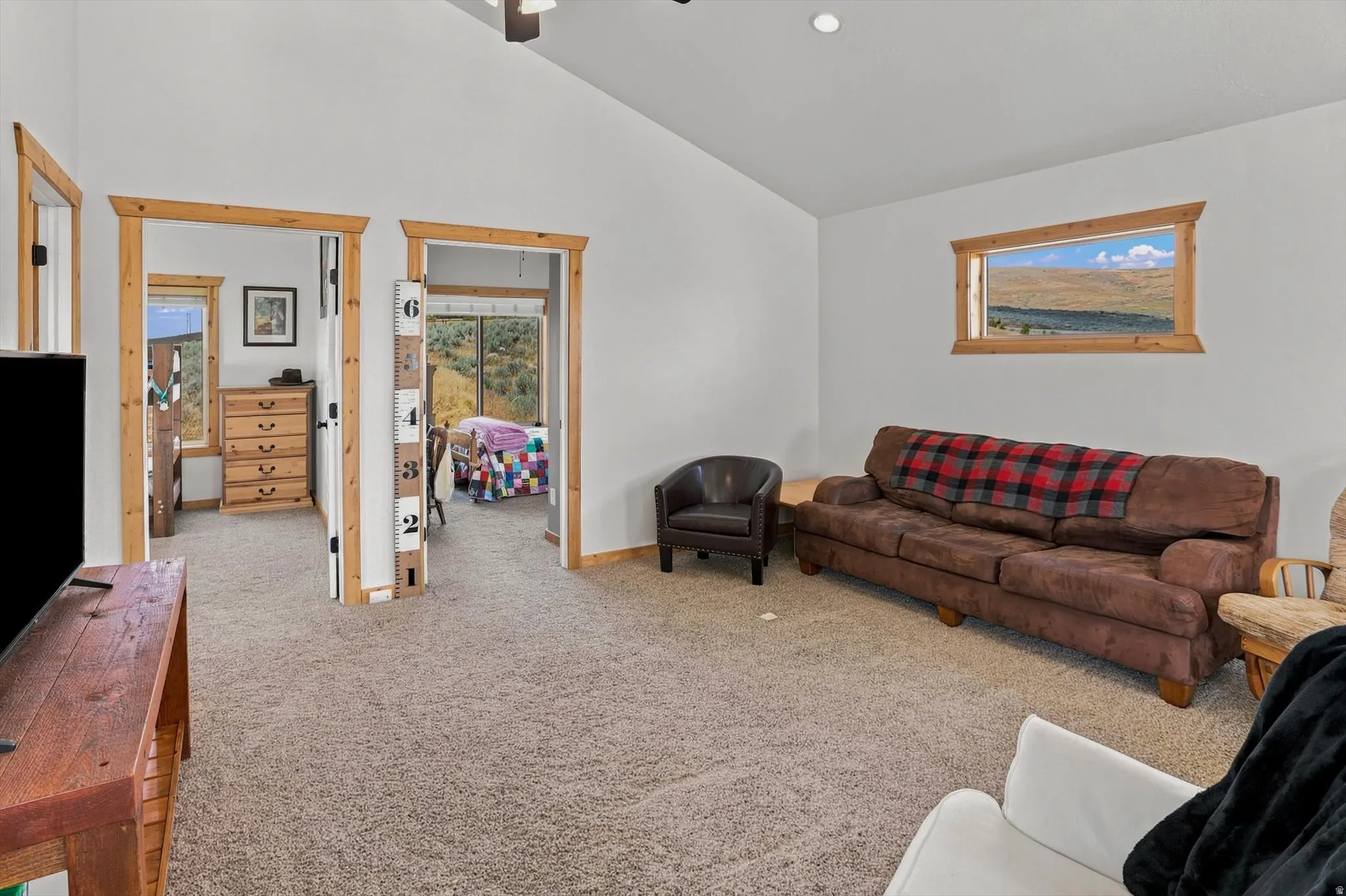 Carpeted interior space featuring white walls and natural wood trim around doorways and a horizontal window