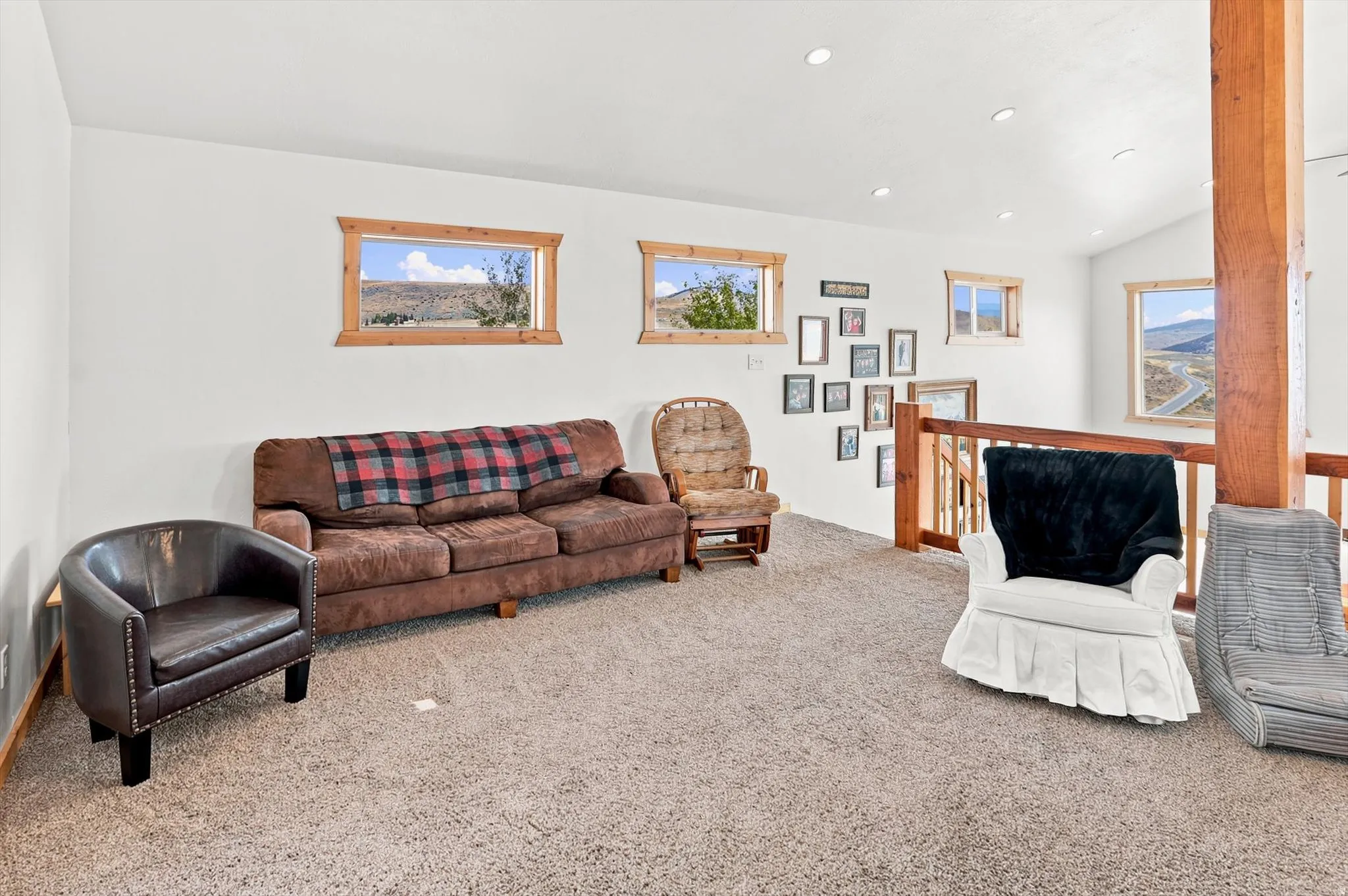 Carpeted loft area featuring multiple windows with wood trim