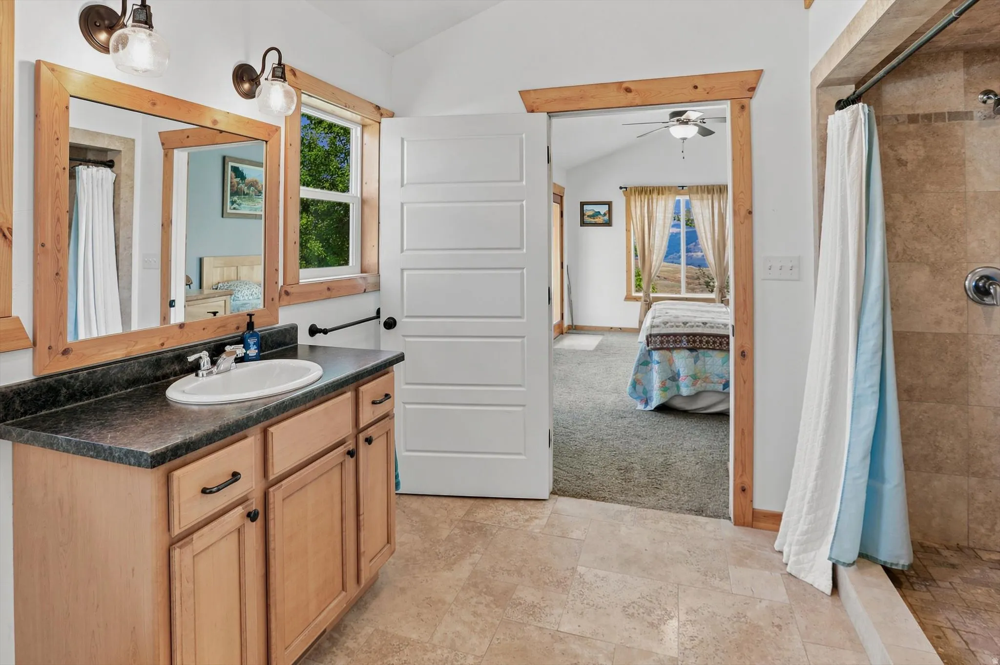 Primary Suite Bathroom featuring a wooden vanity with dark countertop, an oval undermount sink, and two framed mirrors, large step in shower
