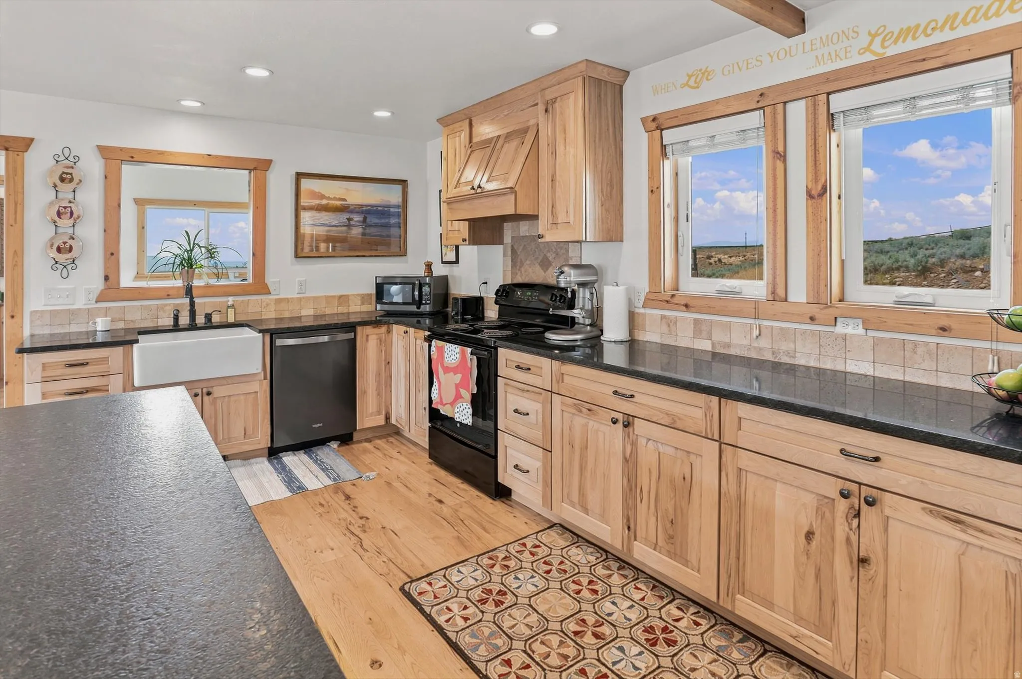 Well-appointed kitchen featuring wood-finish flooring, natural wood cabinetry, dark countertops, and a white farmhouse sink