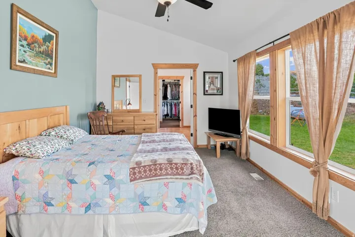 Primary Suite Carpeted room featuring a vaulted ceiling and a ceiling fan