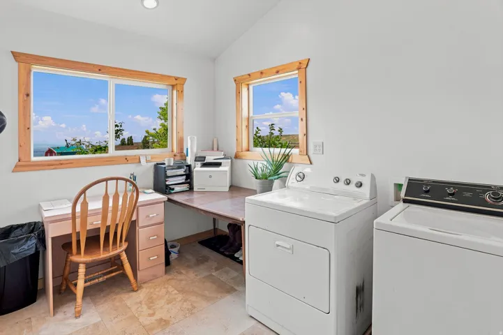 Spacious multi-purpose room featuring a built-in desk, two windows with wood trim, and tile flooring