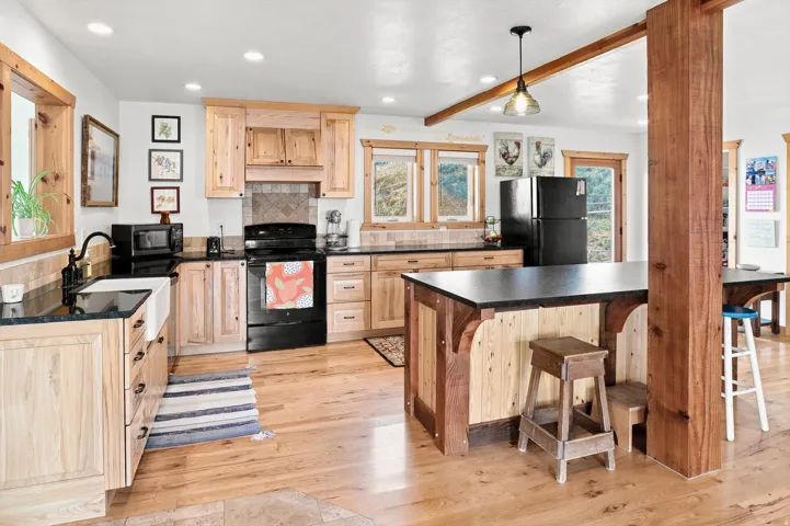 Kitchen featuring wood cabinetry, black countertops, and wood-finish flooring