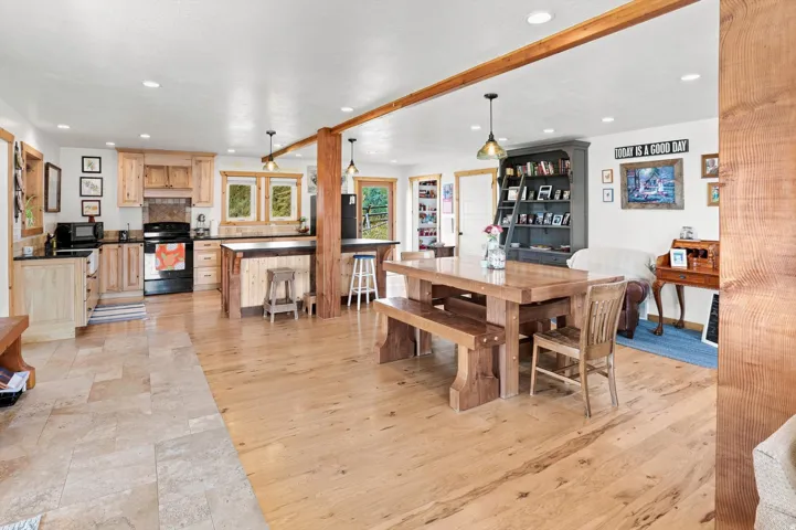 Open-concept living area featuring light wood-finish flooring, recessed lighting, and exposed wood beams