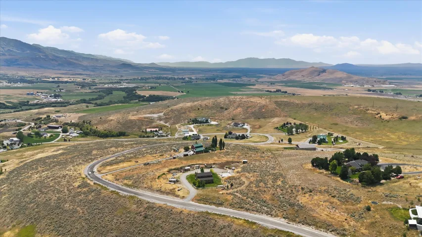 Expansive aerial capturing multiple properties nestled into a landscape featuring rolling hills, distant mountains, and agricultural fields