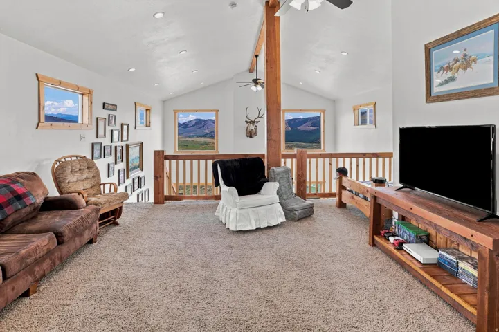 Expansive loft area featuring vaulted ceilings, recessed lighting, and multiple windows with wood-trim framing