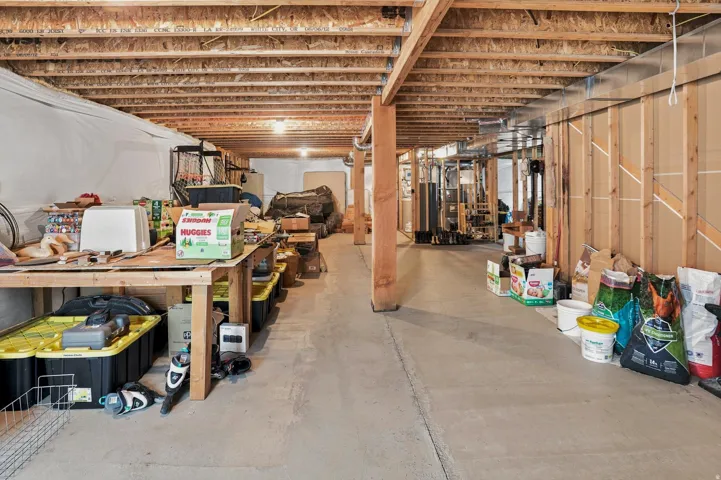 Unfinished basement offering substantial square footage, exposed wooden ceiling joists, concrete flooring, and framed walls