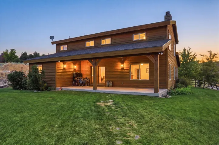 Two-story wood-sided exterior with a covered porch and concrete patio