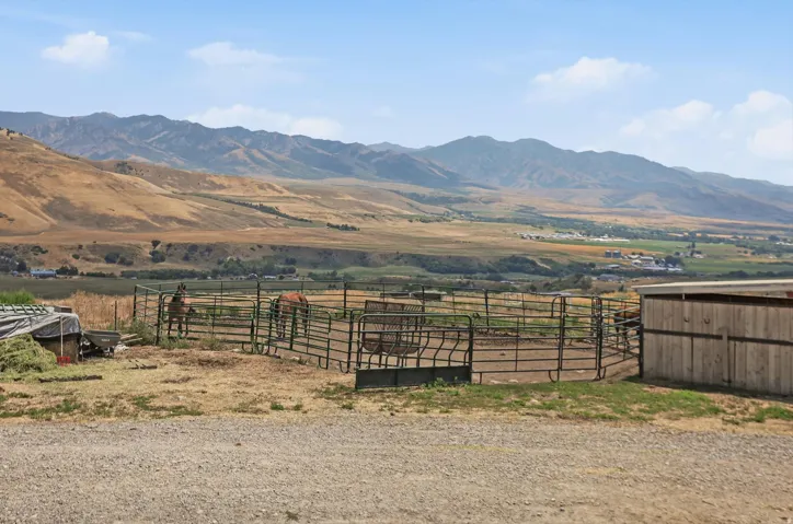 Expansive property featuring a metal fenced corral, a wood-sided outbuilding, and gravel ground cover