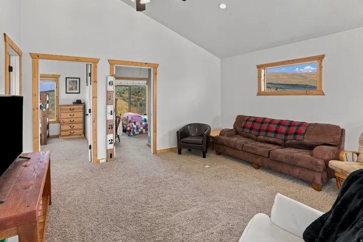Carpeted interior space featuring white walls and natural wood trim around doorways and a horizontal window
