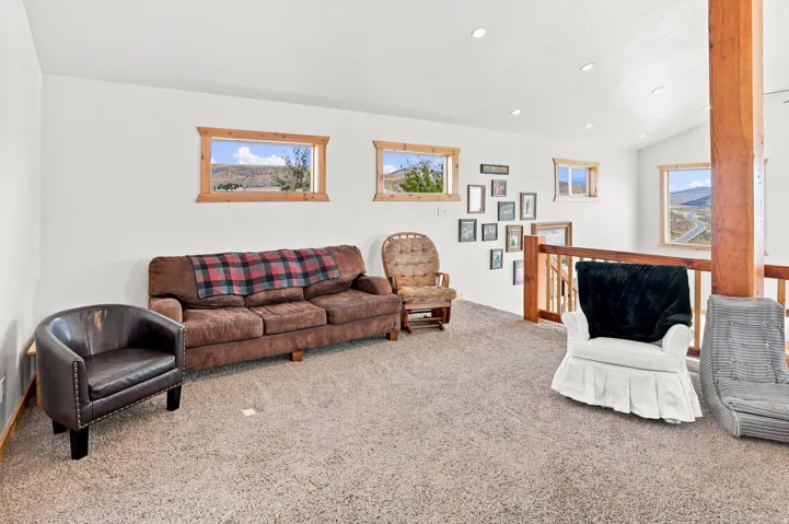 Carpeted loft area featuring multiple windows with wood trim