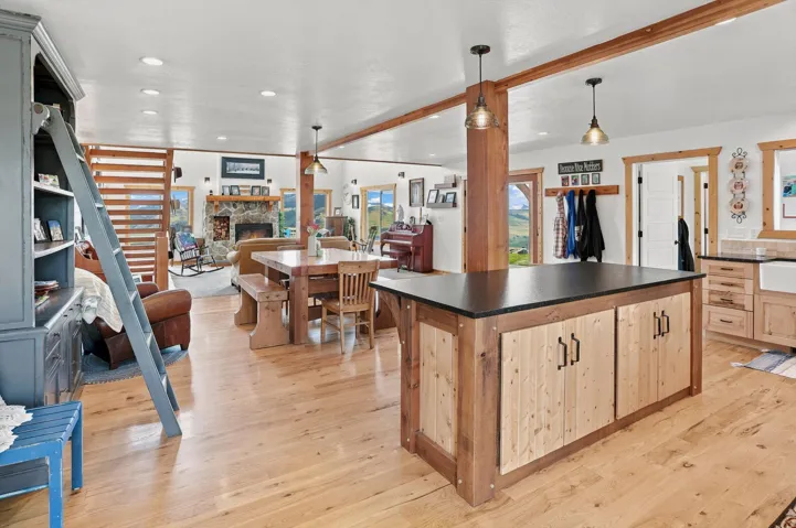 Open-concept living area with light wood-finish flooring, exposed wood beams, and recessed lighting