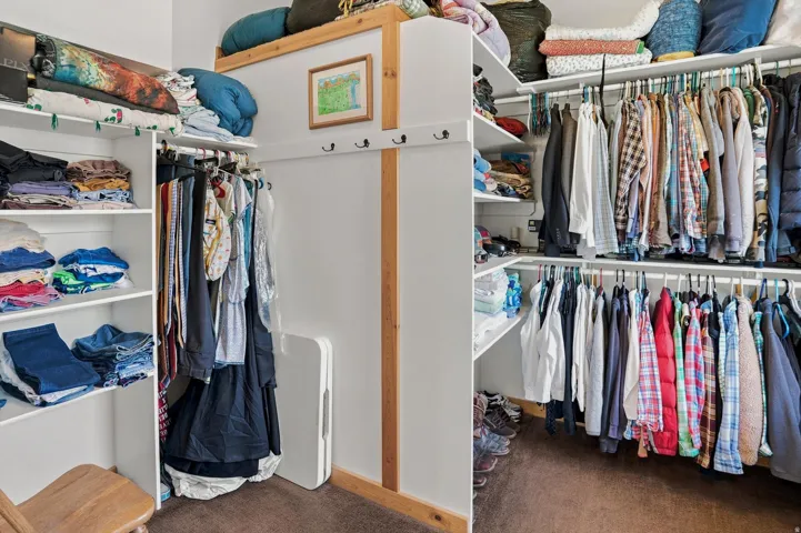 Primary Suite Custom closet system with multiple shelving units, double hanging rods, and integrated upper storage