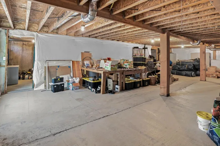 Unfinished basement offering substantial square footage, exposed wooden ceiling joists, concrete flooring, and framed walls