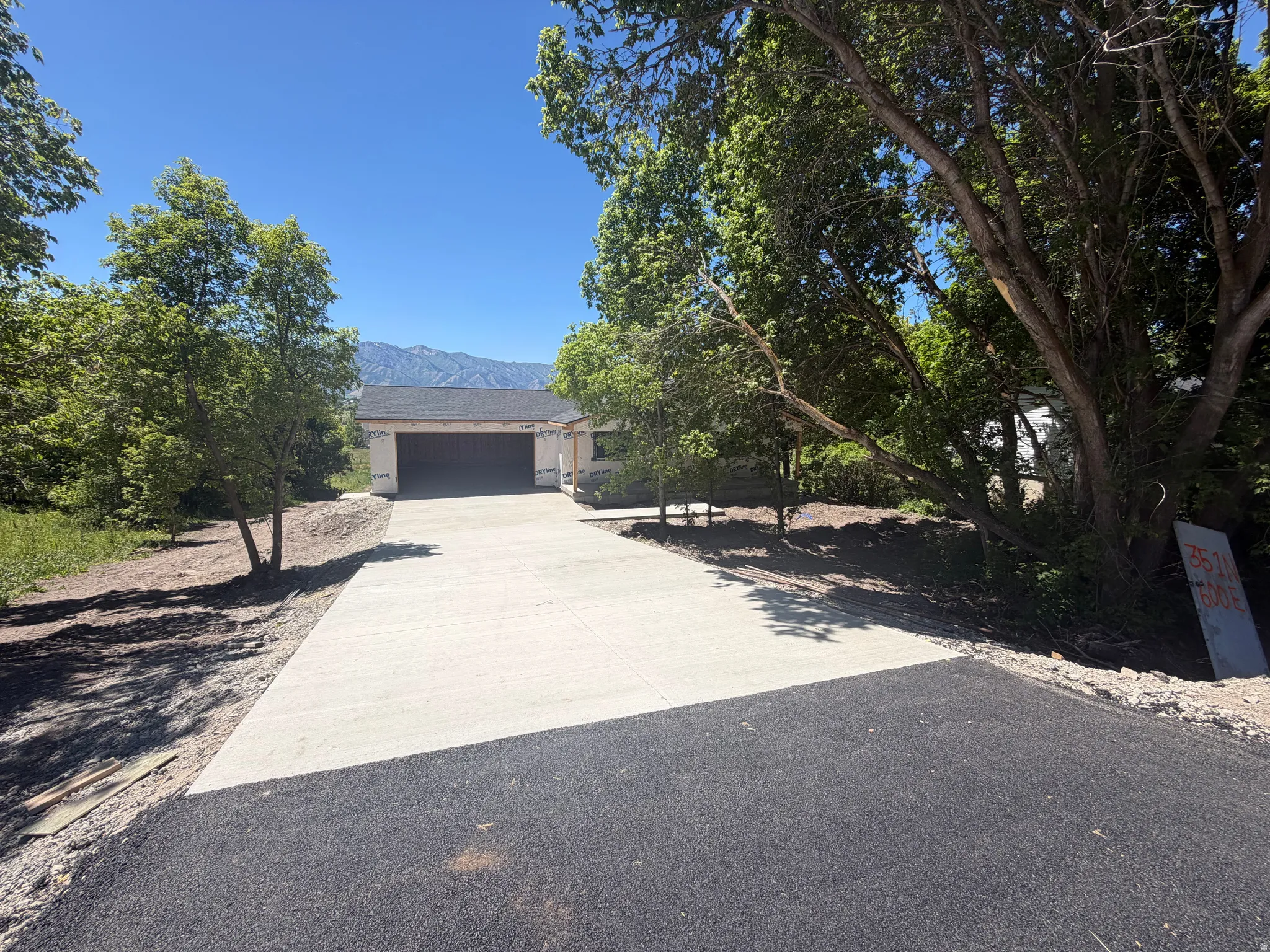 New asphalt and concrete driveway leading to a garage structure