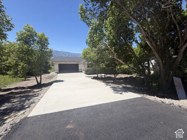 New asphalt and concrete driveway leading to a garage structure