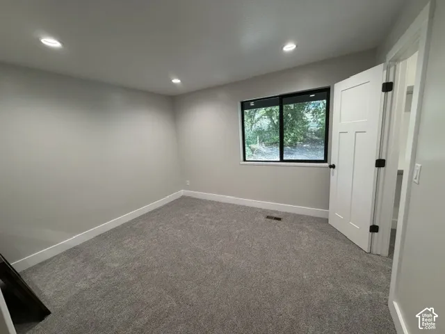 Recessed ceiling lighting, gray carpeting, a window with black trim, and a white interior door with black hardware