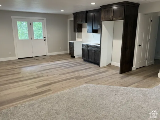 Wood-finish flooring, recessed lighting, and a built-in wet bar with dark wood cabinetry