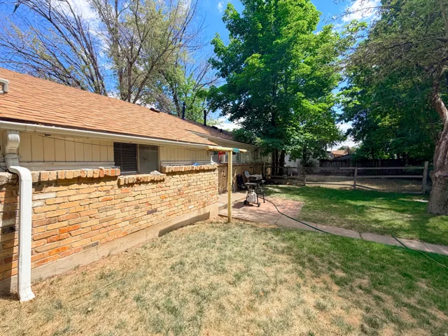 Expansive backyard featuring mature trees, a wood fence, and a concrete patio