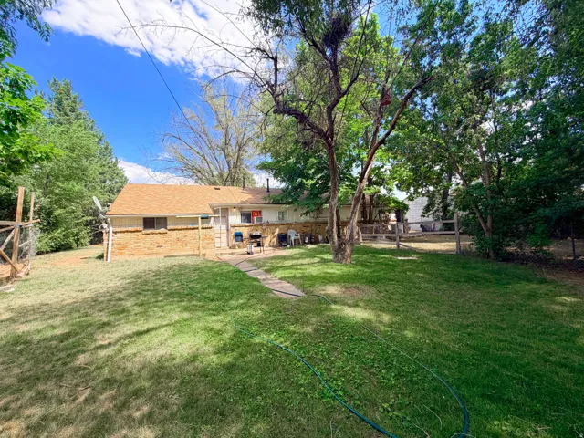Expansive backyard featuring a manicured lawn, established trees, and a flagstone pathway leading to the home
