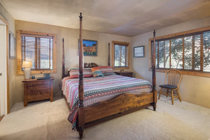 Carpeted bedroom featuring multiple windows with wood blinds and wood trim
