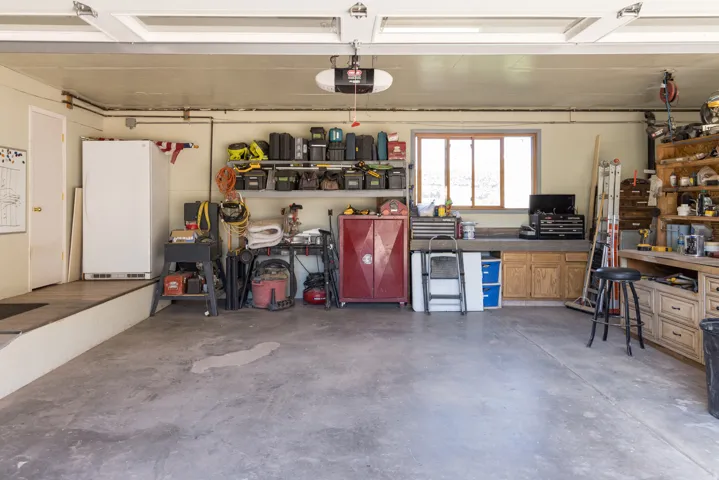 Spacious garage featuring a concrete floor, built-in workbench with storage, window for natural light, and an overhead garage door opener