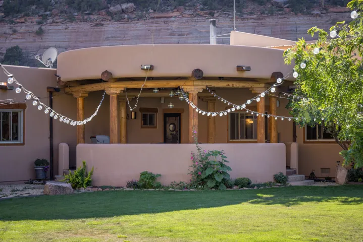 Spacious covered patio with wood columns, a stucco exterior, and a manicured lawn