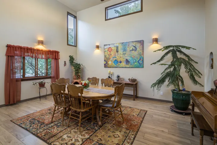 Vaulted ceiling with high windows, wood-finish flooring, and a large window with exterior tree views