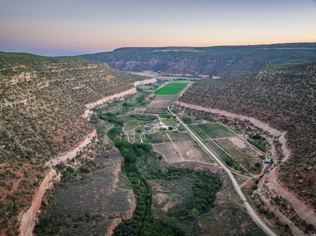 Expansive valley property featuring cultivated fields, natural rock formations, and a winding waterway