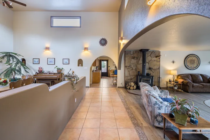 Arched entryway leading to a living area with a stone-clad wood-burning stove, high ceilings, and recessed wall niches