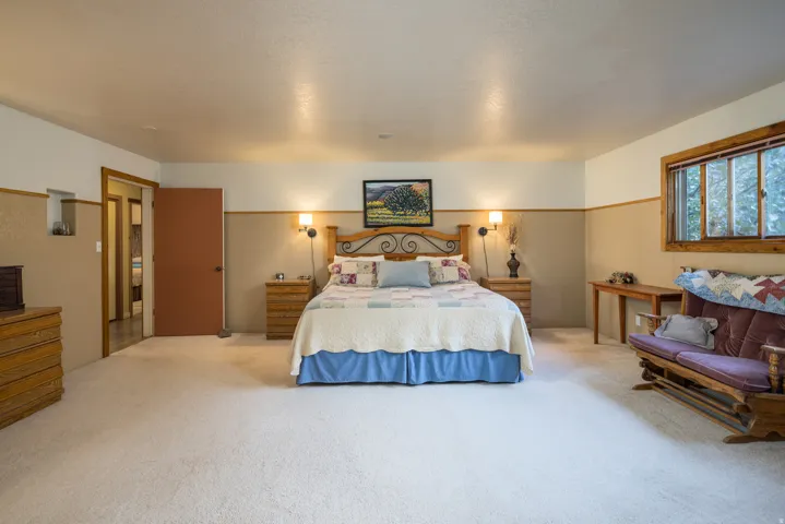 Spacious room featuring neutral carpet flooring, a natural wood-frame window, and a built-in wall niche