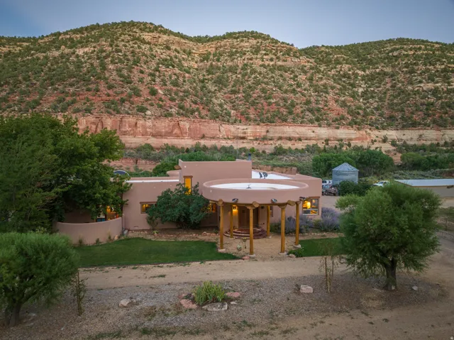 Southwestern-style residence featuring a stucco exterior, a covered circular portico with exposed wood beams, and a gravel driveway