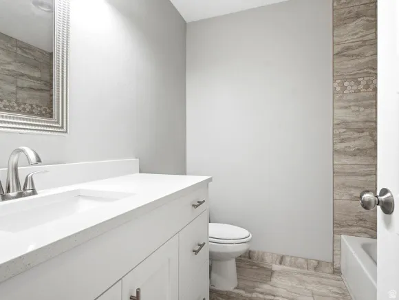 Bathroom featuring a white vanity with an integrated sink, brushed nickel faucet, and a framed mirror