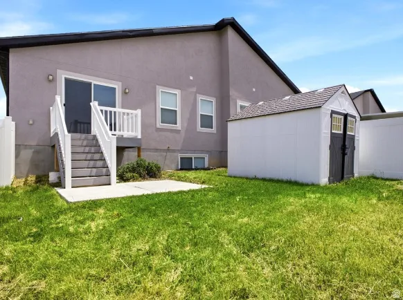 Rear exterior featuring a sliding glass door with balcony, concrete patio, detached shed, and privacy fencing