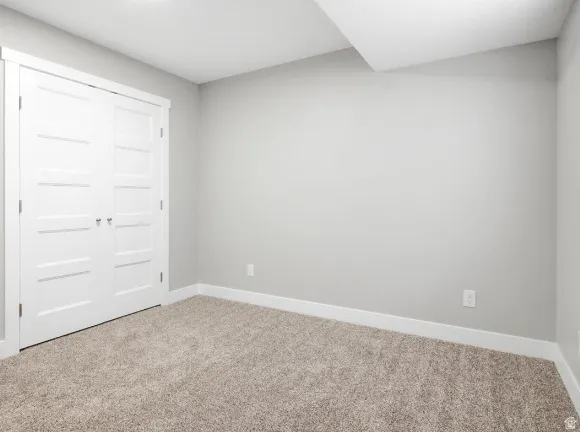 Neutral-toned room featuring light gray walls, plush carpet flooring, and white baseboards
