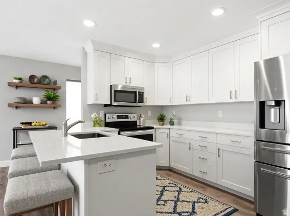 Well-appointed kitchen featuring white cabinetry, light countertops, and stainless steel appliances