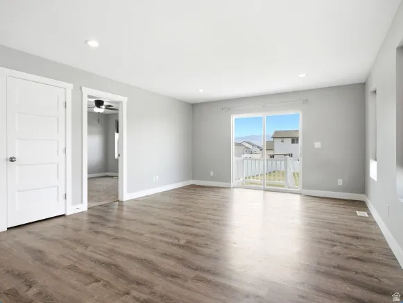 Spacious room featuring wood-finish flooring, light gray walls, and recessed lighting