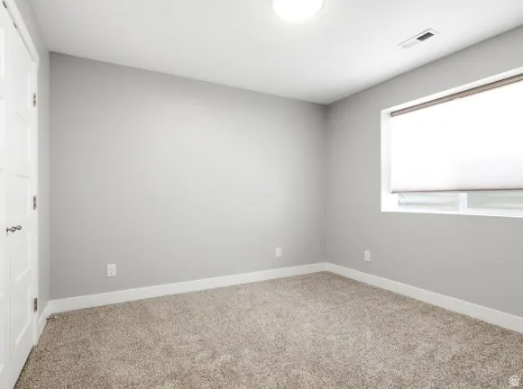 Neutral-toned room featuring light gray walls, plush carpeting, and white baseboards
