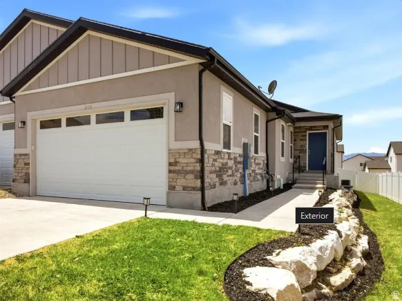 Exterior featuring a two-car garage with transom windows, a blue entry door, and a concrete walkway