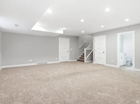 Spacious room with plush carpeting, recessed lighting, and a neutral wall color