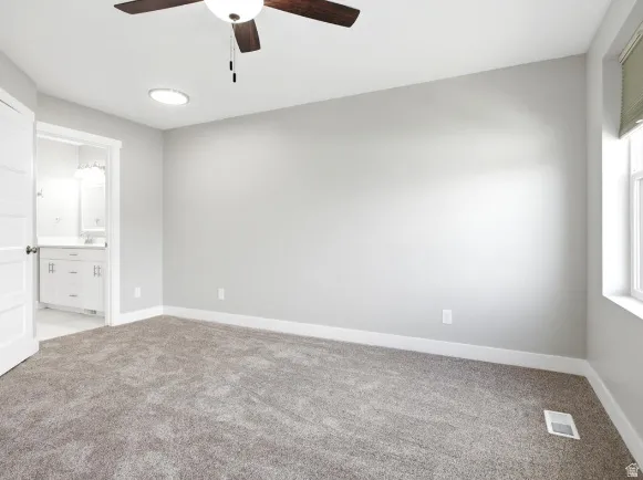 Carpeted room with light gray walls, white baseboards, and a ceiling fan with wood-finish blades