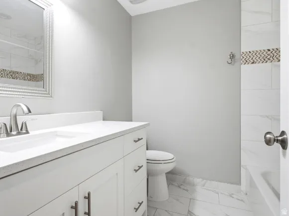 Bathroom featuring a white vanity with brushed nickel hardware, a rectangular undermount sink, and a light-toned countertop