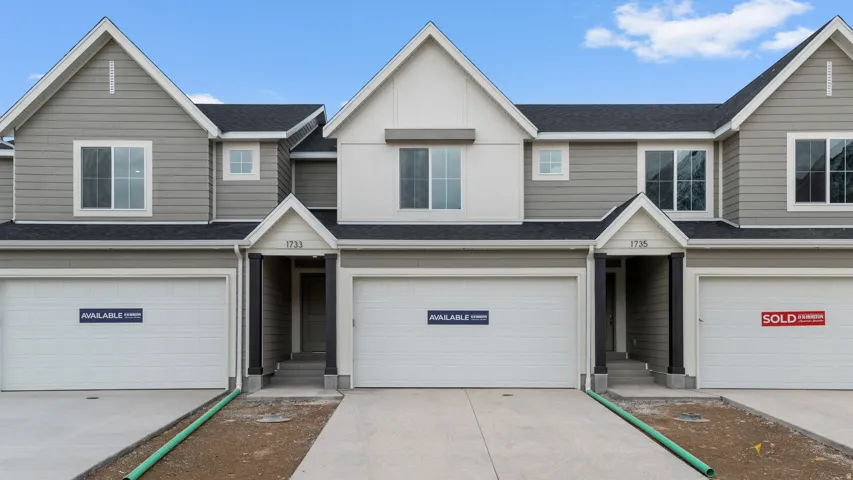 Modern townhome exterior featuring gray horizontal siding and contrasting white trim