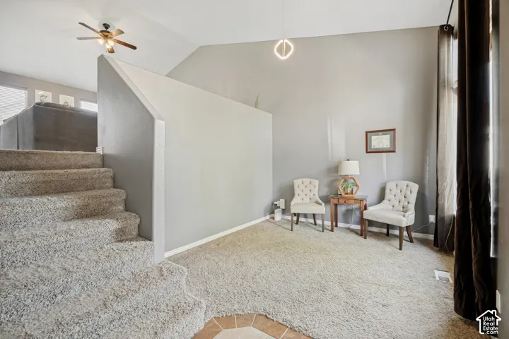Carpeted staircase with an adjacent wall, featuring a modern ceiling fan in the upper space