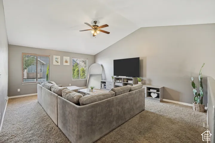 Spacious room featuring a vaulted ceiling and a ceiling fan with integrated lighting