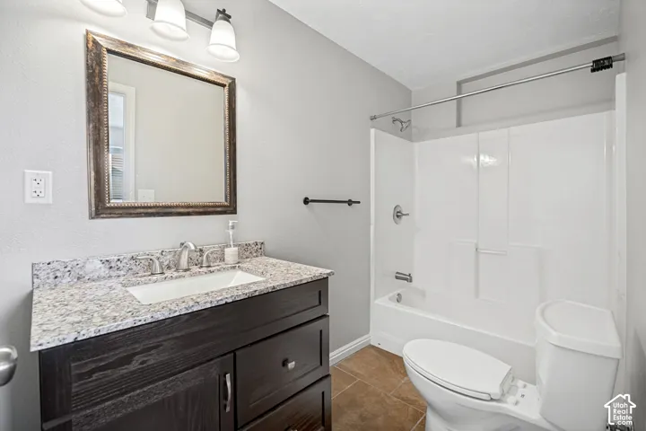 Bathroom featuring a dark wood-finish vanity with an integrated sink, a speckled countertop, and a framed mirror