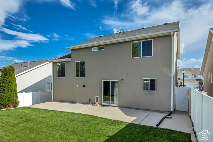Rear exterior featuring a stucco finish, multiple windows, and a sliding glass door