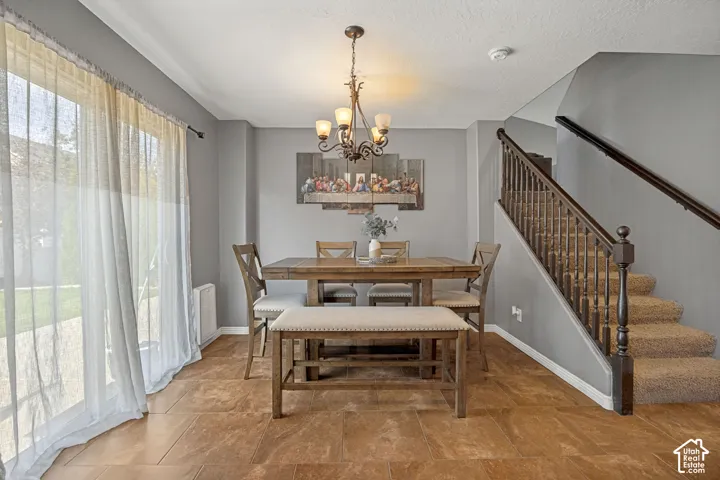 Dining area featuring tile flooring, a multi-light chandelier, and a sliding glass door