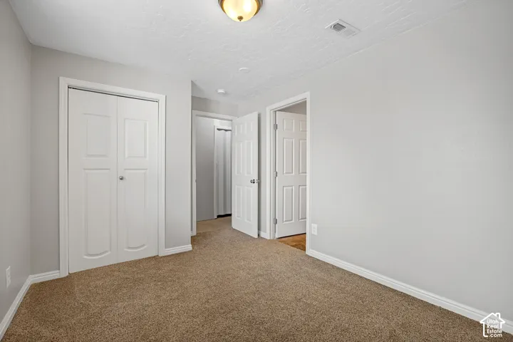 Room featuring light gray painted walls, a textured ceiling, and brown carpet flooring
