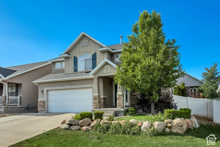 Two-story residence featuring a neutral stucco and stone facade with a prominent front-facing gable